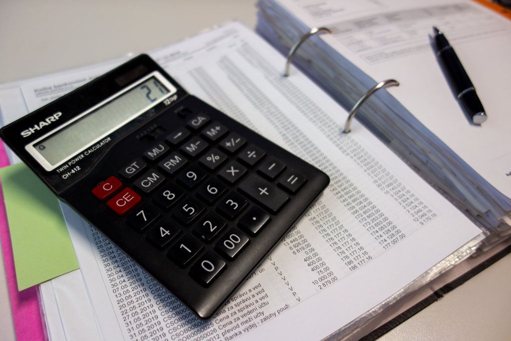 Калькулятор со ставкой налога 21% на балансовой ведомости на столе бухгалтера